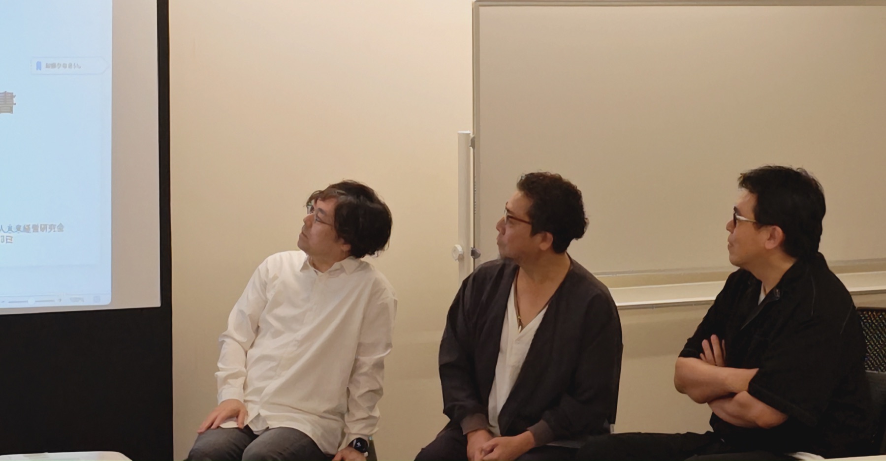 第1回 公開メディア会議。パネラー3名が同じスクリーンを見ながら、それぞれの視点で考える様子